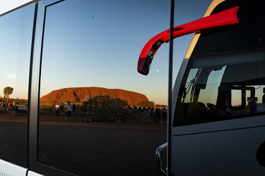 A reflection of Uluru in a tour bus parked at the Uluru bus sunset viewing area.   Tourists are rushing to climb world heritage-listed Monolith, Uluru in Australia's central desert before a ban on c...