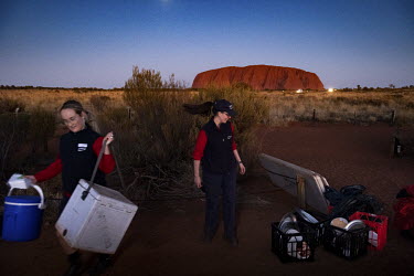 Bus tour staff pack up the refreshment tables, long after the last bus has left the Uluru bus sunset viewing area.   Tourists are rushing to climb world heritage-listed Monolith, Uluru in Australia'...