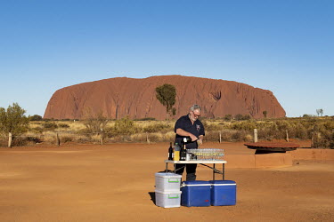 A tour operator prepares drinks for his guests at the Uluru bus sunset viewing area.  Tourists are rushing to climb world heritage-listed Monolith, Uluru in Australia's central desert before a ban o...
