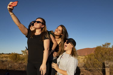 Tourist pose for a selfie at the Uluru bus sunset viewing area.   Tourists are rushing to climb world heritage-listed Monolith, Uluru in Australia's central desert before a ban on climbers takes eff...