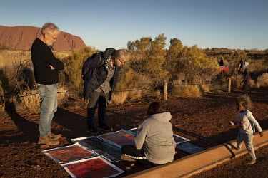 Tourists inspect local Aboriginal art for sale in the Uluru bus sunset viewing area.   Tourists are rushing to climb world heritage-listed Monolith, Uluru in Australia's central desert before a ban...