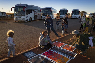 Tourists inspect local Aboriginal art for sale in the Uluru bus sunset viewing area.  Tourists are rushing to climb world heritage-listed Monolith, Uluru in Australia's central desert before a ban o...