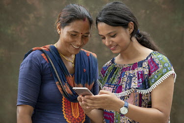 Farmer Sita Kumari looks at a mobile phone application with Pratima Baral, a data scientist. Mobile phone technology is helping Sita enhance crop yields and get access to markets.