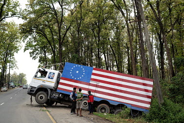 A BharatBenz 3123 truck, decorated with an American flag, Confederate flag, lies in a roadside ditch following an acident.