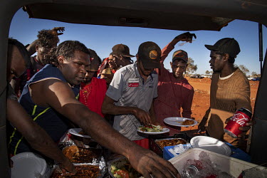 Shortly after a game the Lajamanu Australian Rules Football team lines up for a group lunch, served from the back of a car.  Once a year Football teams from all over Central Australia travel to part...