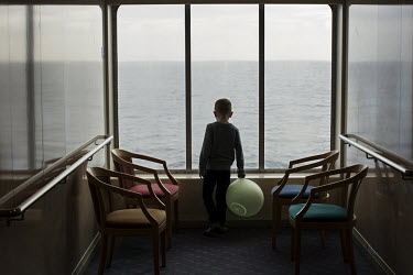 A young boy looks out of a window while travelling on the ferry that takes passengers between the capital Torshavn and the southernmost island Suduroy.
