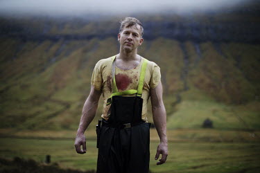 Hjalmar, his shirt stained with blood during sheep slaughtering on a farm.