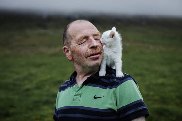 Andrias Justesen (54) with his little white pet kitten outside his home, which he shares with his mother (82) and several cats. Andrias went to Denmark to study to become a teacher, because his mother...
