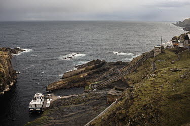 A ferry boat carrying people and supplies moors at a small harbour on Mykines. The island is about 10 square kilometers, and is the western most island of the Faroe Islands.