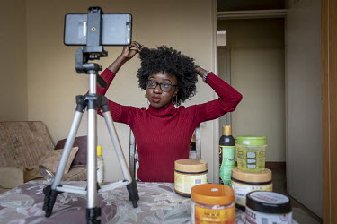 Peace Joice, who blogs about hair, records new footage, at her home, for a video about her hair.
