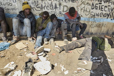 A group of street children who have been inhaling glue sit beside a graffiti covered wall under a bridge near the Cairo Road.
