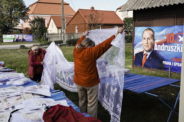 People looking through clothing and materials for sale at the street market, surrounded by posters for the 13 October 2019 elections.