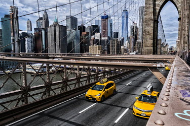 Yellow taxi cabs cross on the lower level of the Brooklyn Bridge.
