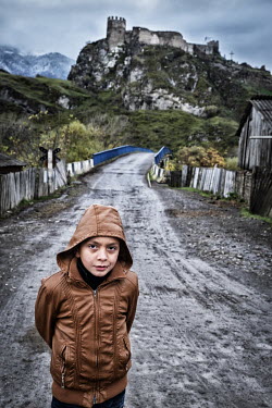 A boy stands on a rural road leading to the 10th century fortress of Atskuri.