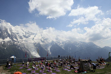 A yoga class takes place on a terrace overlooking the mountains at the Chamonix Yoga Festival.