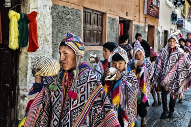 Quechua Indian boys, blowing conch horns, parade during a Sunday celebration.