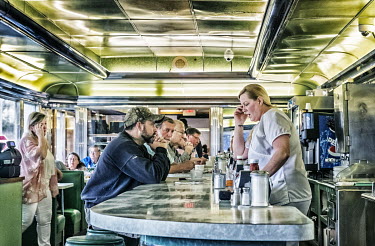 Customers waiting to be served at the counter in a vintage diner.