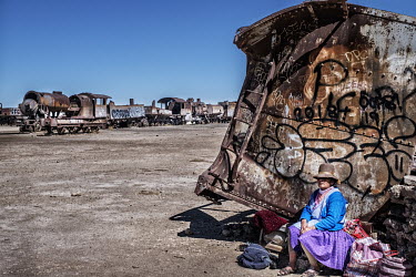 An Indian woman seling handicrafts to tourists who are attracted by a collection of discarded steam locomotives that were once used to transport minerals excavated locally. They have fallen into disus...