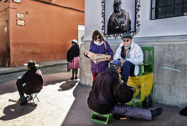 A shoe-shiner and a beggar on a street corner in the Spanish-built historic centre of potosi.