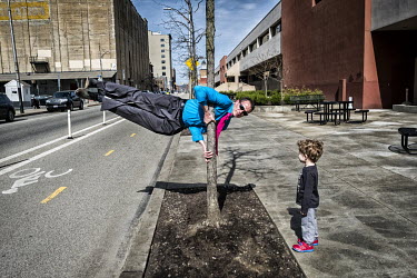 A father shows his son acrobatic tricks on the pavement.