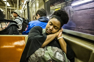 A woman sleeps on a subway train.