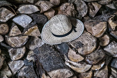An Amish man's straw hat lying on a pile of fire wood.
