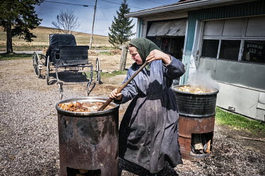 An Amish woman stirs a boiling barrel full of pork fat which she will use to make soap.