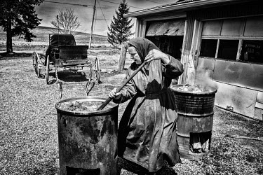 An Amish woman stirs a boiling barrel full of pork fat which she will use to make soap.