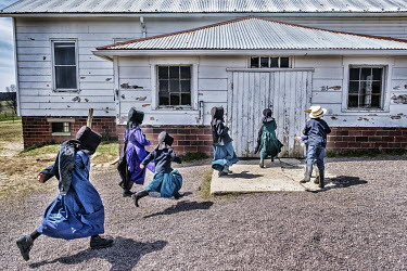Amish school children run to the school building at the end of their playtime.