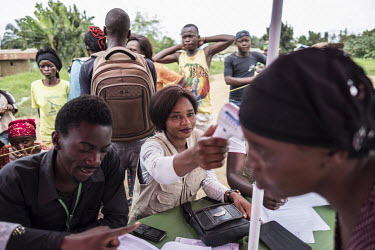 A staff member, working for Catholic charity Caritas, takes a woman's temperature at a food distribution site in the Ebola-hit town of Mambasa.