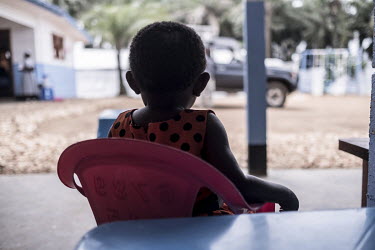 A child whose parents are in an Ebola treatment centre sits on a chair in the adjacent Caritas-supported nursery.