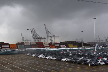 Rows of newly made Honda cars are lined up in the docks at the port in Southampton prior to export. Beyond, are stacks of shipping containers and the gantry cranes that load and unload them from cargo...