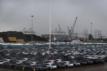 Rows of newly made Honda cars are lined up in the docks at the port in Southampton prior to export. Beyond, are stacks of shipping containers and the gantry cranes that load and unload them from cargo...