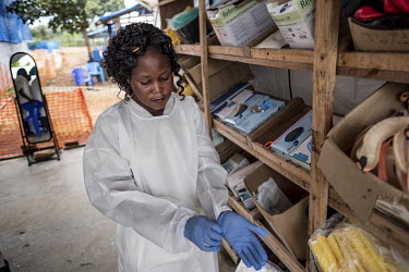 Estelle Uweka (27), an Ebola survivor and health worker puts on PPE (personal protection equipment) including a pair of latex gloves as she prepares to visit a patient in the 'red zone' at the Ebola t...
