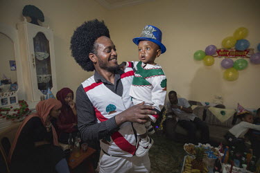 A father and his son at a birthday party where they are both dressed in the colours of the Oromo flag.