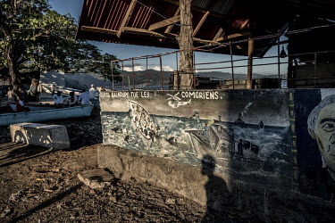 Graffiti condemning the French policy of restricting free travel between Mayotte and the Comoros on a wall in Ouani. The graffiti shows migrants being eaten by sharks at sea, while a French officer fi...