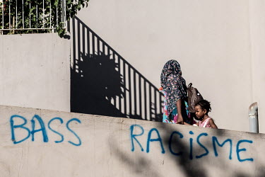 A mother and daughter walk past anti-racism graffiti in Mayotte.