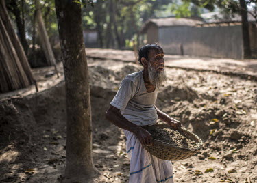 Abdul Khader, who has been blind since childhood, carries buckets of sand to a building site in his compound.