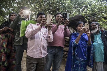 A group of villagers take out their mobile phones to take pictures.