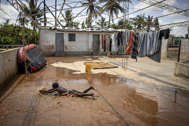 A boy from a family who stayed in the village swimming in a shallow pool of water left behind on the concrete floor after a rain shower. Most families left the village after the Pungwe River broke its...