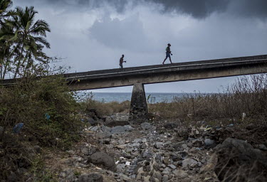 People walk over a bridge across a dried up river. Deforestation has led to the loss of up to three quarters of the islands permanent rivers in just 50 years.