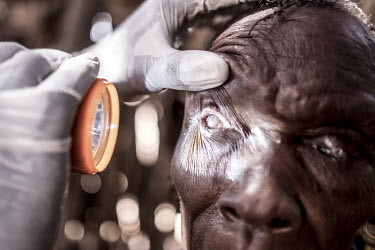 Community health volunteer James Lomuria examines the eyes of Akai Ekiru, who is now irreperably blind due to trachoma.