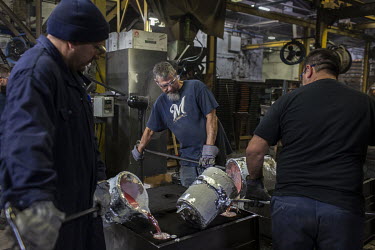 Employees Robert Flores (L), Ace Waak (centre) and Marcos Alfaro pour molten aluminum, at 760 Celsius, that will be made into an engine housing component at the Wisconsin Aluminum Foundry. The factory...