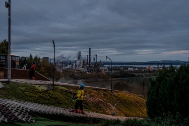 A boy skis on the artificial slopes at Polmonthill Ski Centre. In the background is the refinery at Grangemouth.
