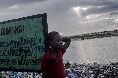 A boy stands on a rubbish heap in the Ebola hit slum neighbourhood of West Point.