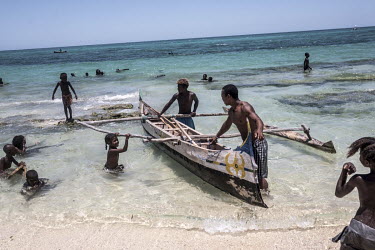 A traditional outrigger fishing boat returns to shore.
