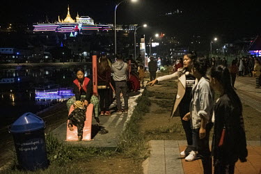 Young people enjoy cool weather in the evening in Mogok city centre beside a small lake that was formerly an open-cast ruby mine during the British colonial-era. The monastery on the hillside behind i...