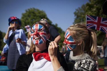 Claire Kirkpatrick has her face painted by friend Katie Davis as they sit among the crowds gathered in Windsor on the morning of the 19 May 2018 for the Royal Wedding between Prince Harry and Megan Ma...