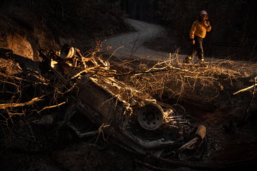 A member of the Rural Fire Service (RFS) inspects the wreck of a small RFS firefighting truck, from the Nowra RFS Brigade, that rolled off the dirt track while fleeing a house as the Currowan fire app...