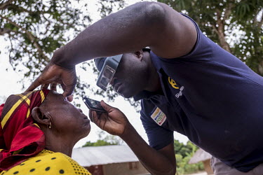 At a screening camp, provincial head of ophthamology, Mai Mai Linha, examines Rosa Manque's eyes with the aid of a mobile phone's torch and a magnifying headset.